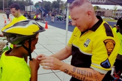 Bridgeport Police Officer fitting a bicycle helmet on a young boy.